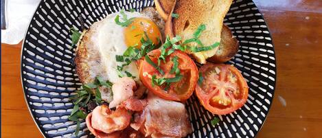 A plate with a fried egg, bacon, tomatoes, and toast.