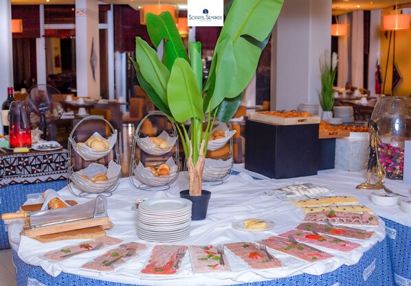 A buffet table with various food items and a decorative plant.