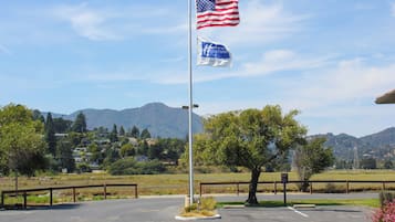 Un mât sur lequel flottent le drapeau américain et le drapeau de l’hôtel, entouré d’un parking avec une chaîne de montagnes en arrière-plan.