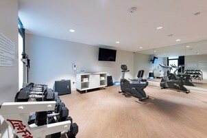 Un gimnasio con equipo de ejercicio, un televisor y un espejo.