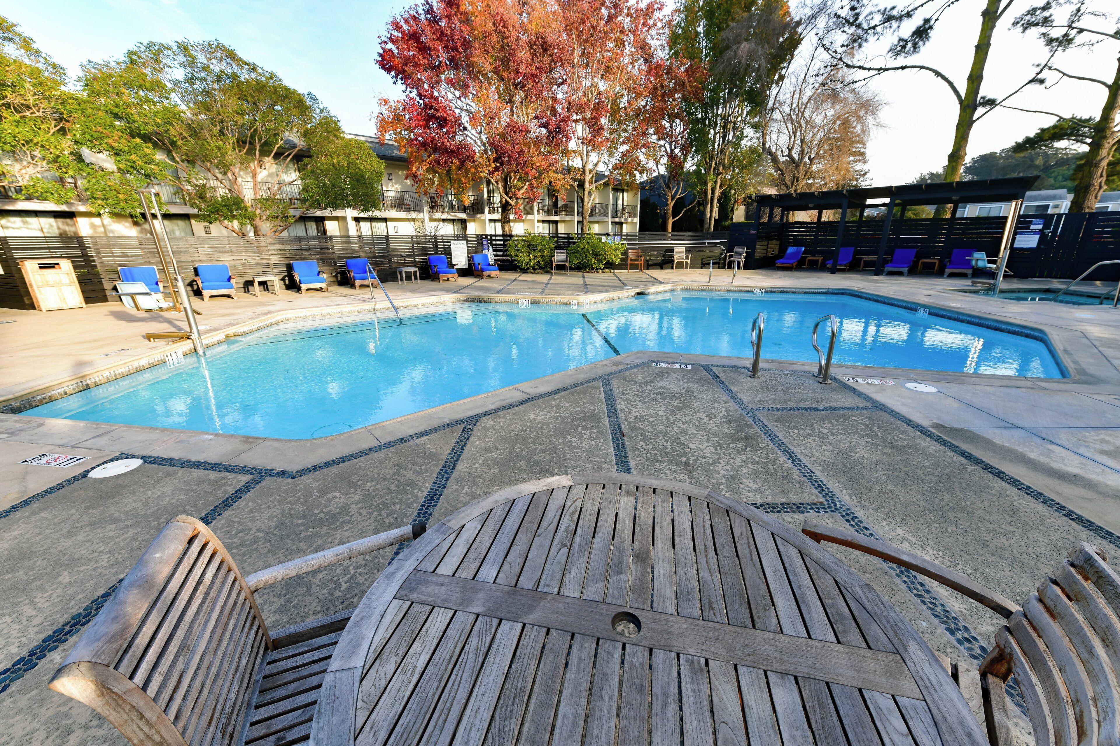 Une piscine avec une terrasse en bois et des chaises longues.