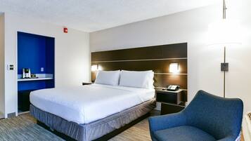 Habitación de hotel con una cama grande, una pared azul decorativa, una zona de estar y una mesita de noche con lámpara.