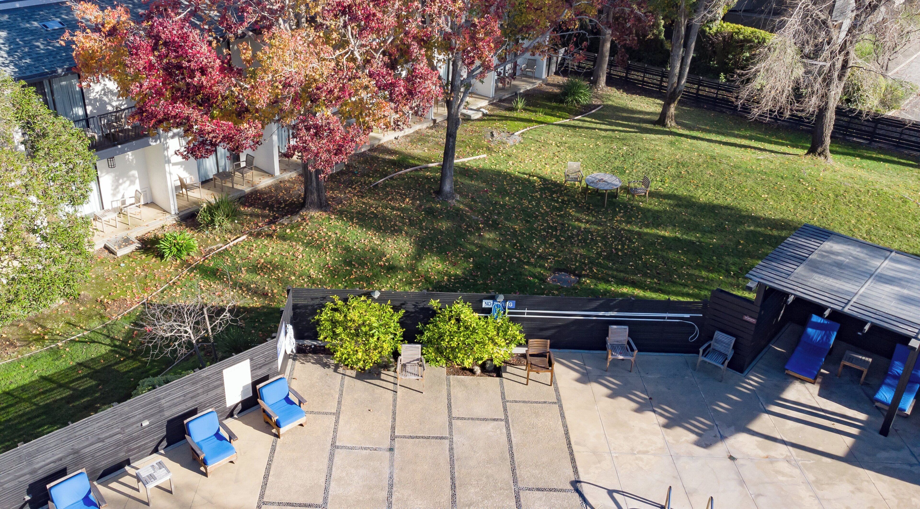 A backyard with a patio area, a covered seating area, and a lawn.
