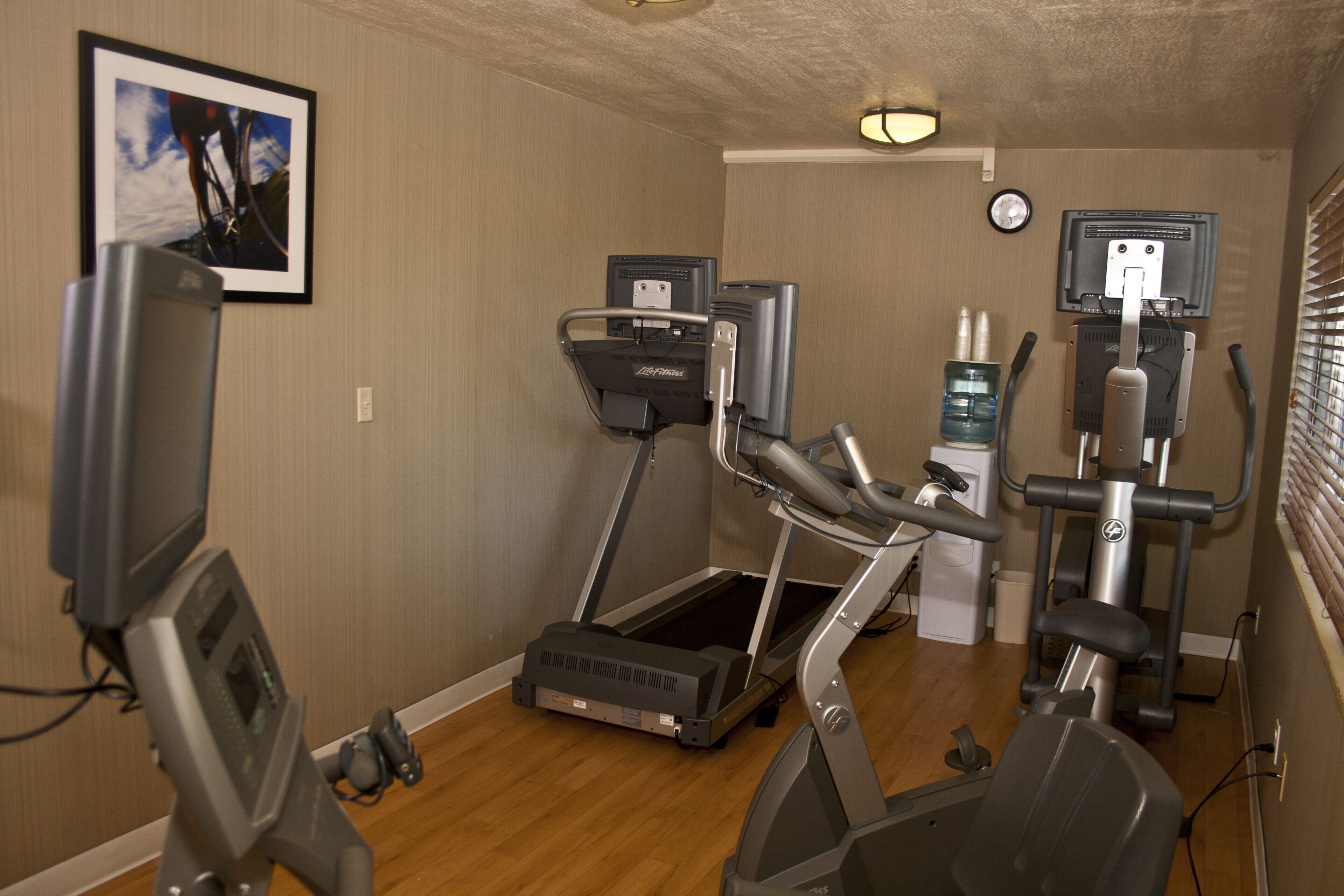 A fitness room with treadmills, a stationary bike, and a water dispenser.