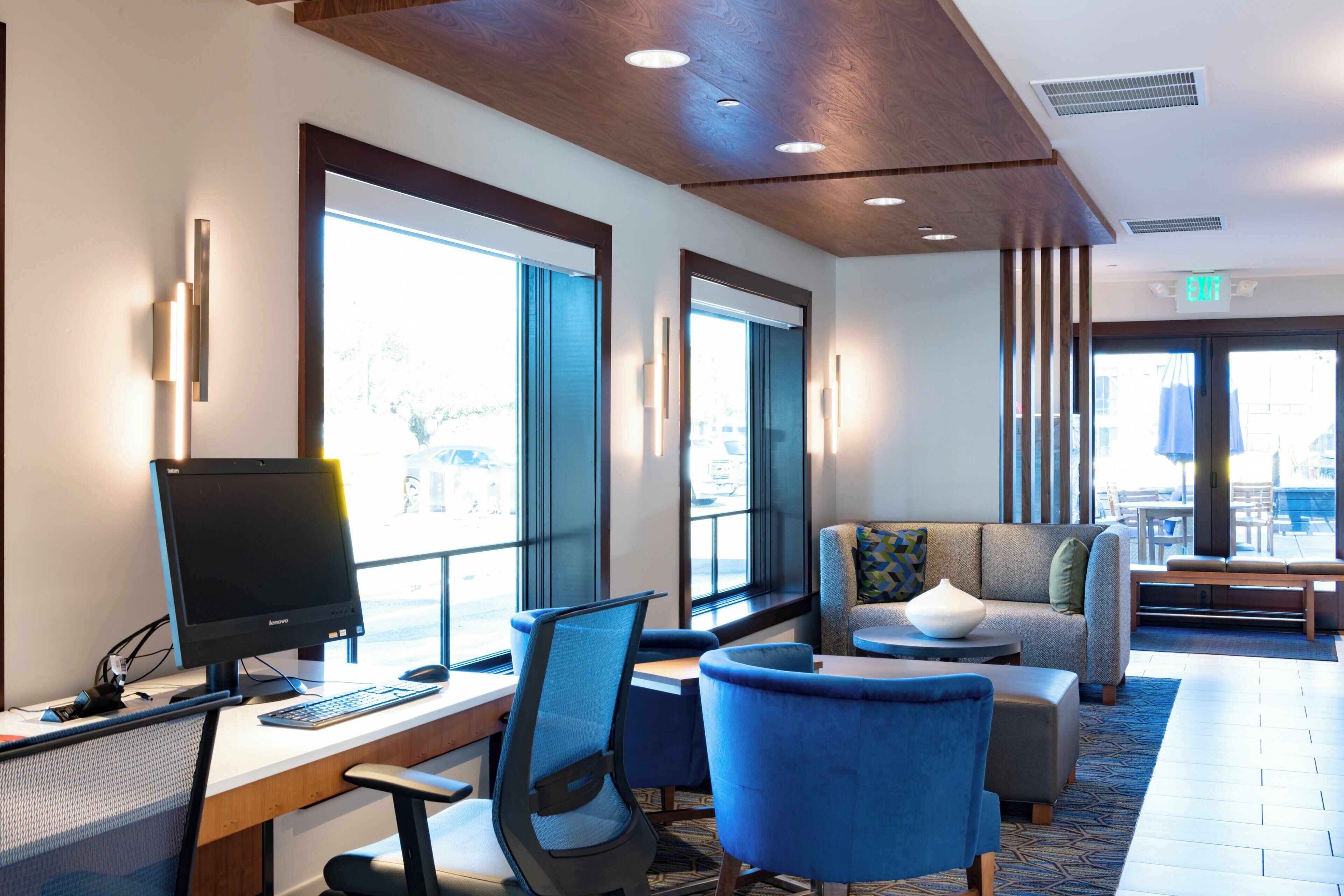 A hotel lobby with a desk, computer, and seating area.