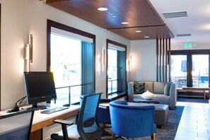 Un hall de hotel con mostrador de recepción, computadora y zona de estar.