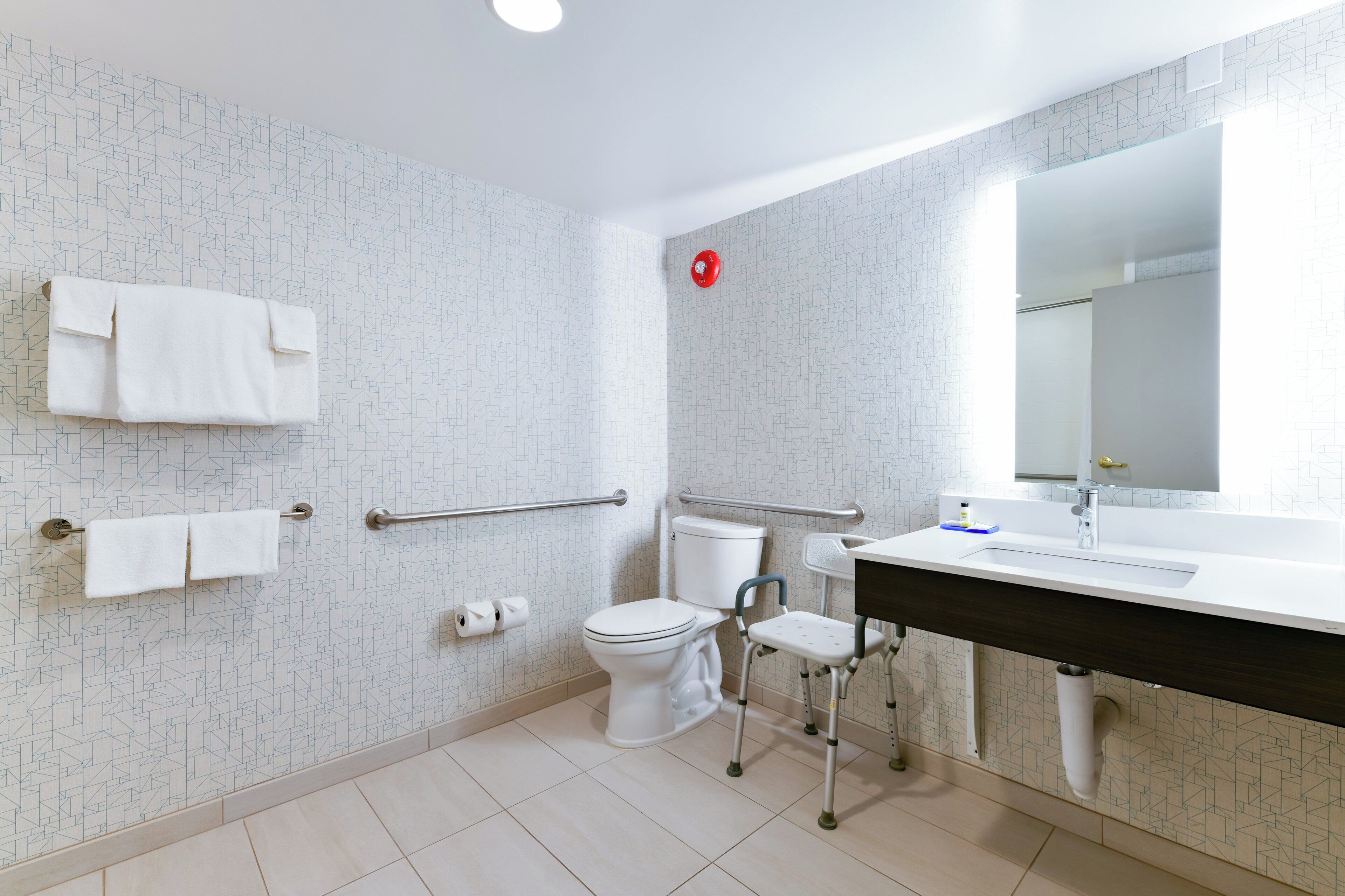 A modern bathroom with a white toilet, a sink with a mirror, and a shower area.