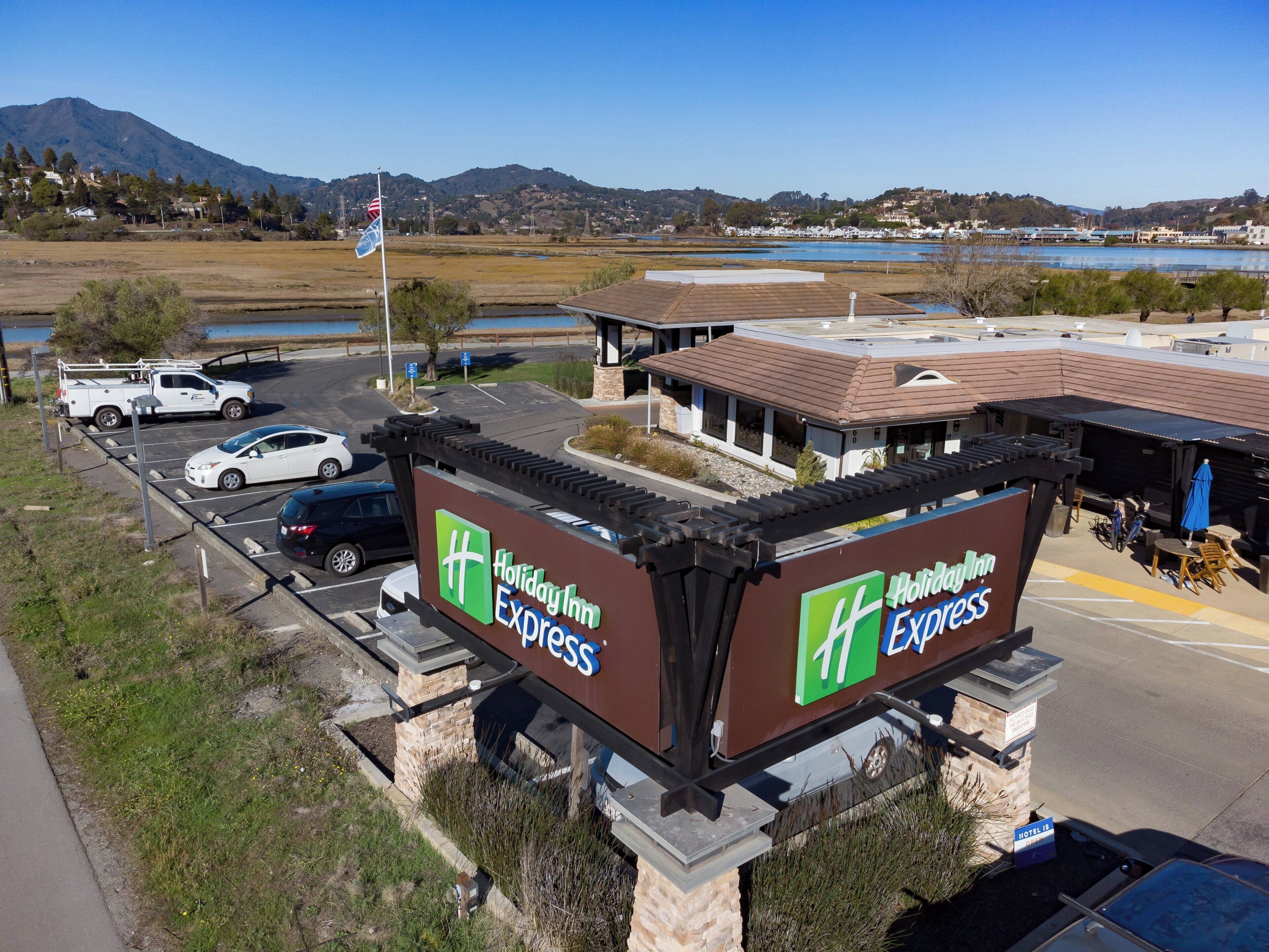 A Holiday Inn Express sign with a view of a parking lot and a building in the background.