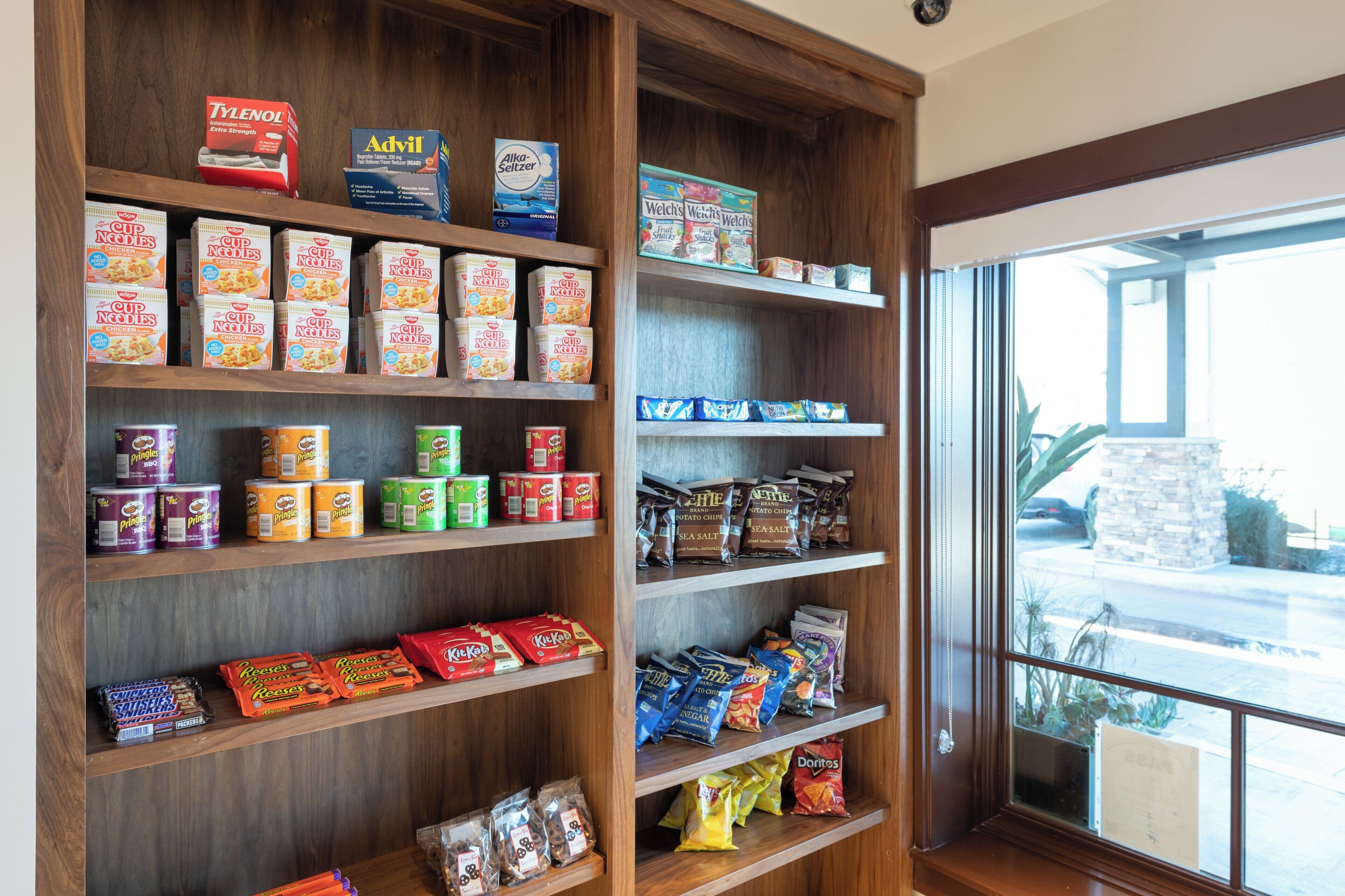 Interior de una tienda con estantes llenos de diferentes productos alimenticios y un ventanal a la calle.