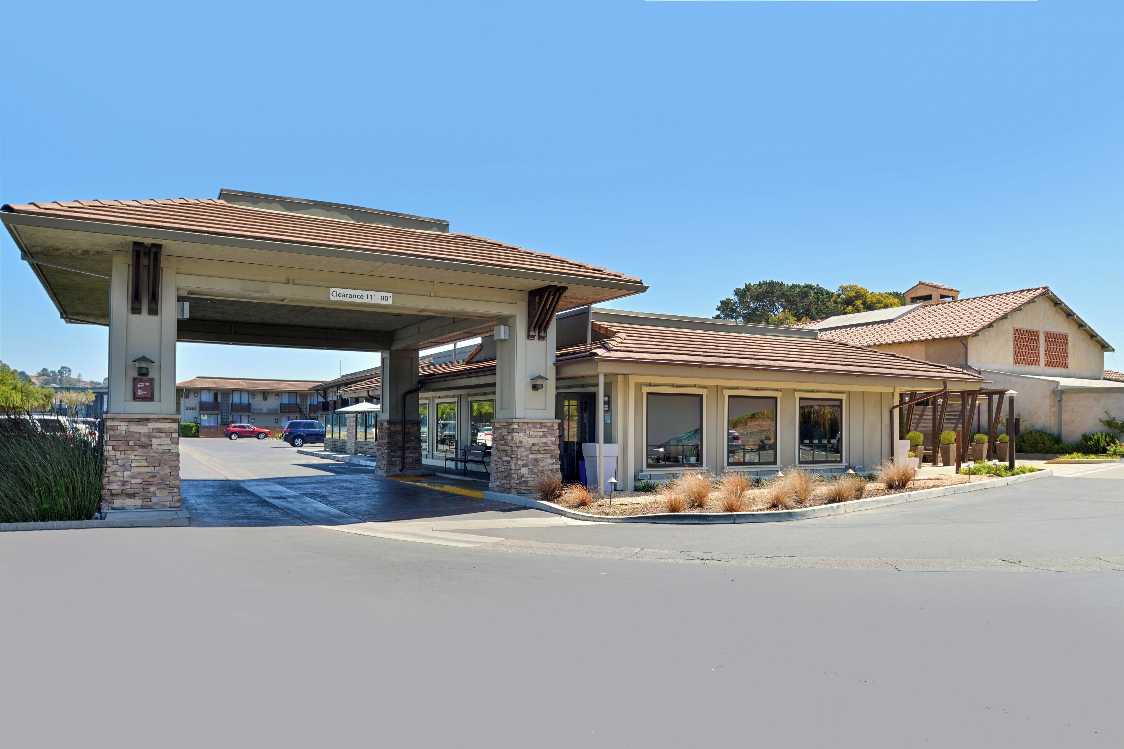 A building with a covered entrance, stone pillars, and a clear sky.