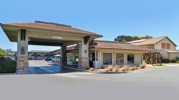 A building with a covered entrance, stone pillars, and a clear sky.
