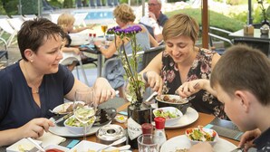 Une table à manger avec différents plats, une bouteille de vin et un vase rempli de fleurs.