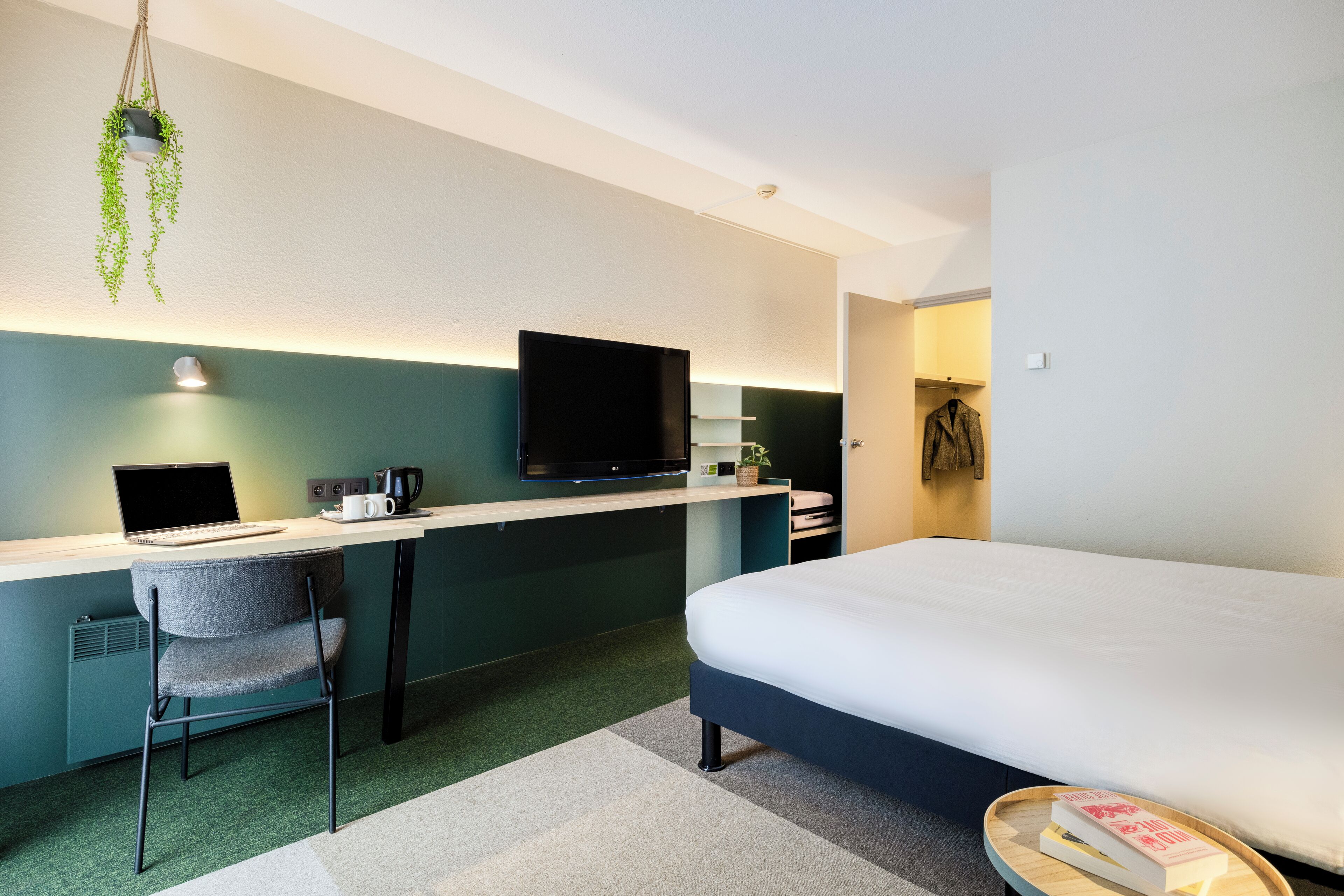 Une chambre d’hôtel moderne équipée d’un lit, d’un bureau, d’une chaise et d’un téléviseur.