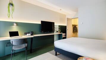 Une chambre d’hôtel moderne équipée d’un lit, d’un bureau, d’une chaise et d’un téléviseur.