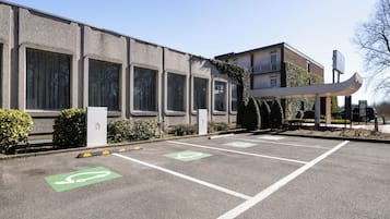 A parking lot with designated bicycle spaces and a building with large windows and a covered walkway.