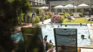 Un espace piscine avec des chaises longues et des parasols.