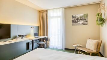 Una camera d'albergo con un letto, una scrivania, una sedia e un televisore.