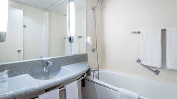 A modern bathroom with a granite sink, a handheld showerhead, a built-in bathtub, and a towel rack.