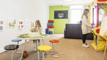 Una sala giochi con un tavolo, sedie e un canestro da basket.