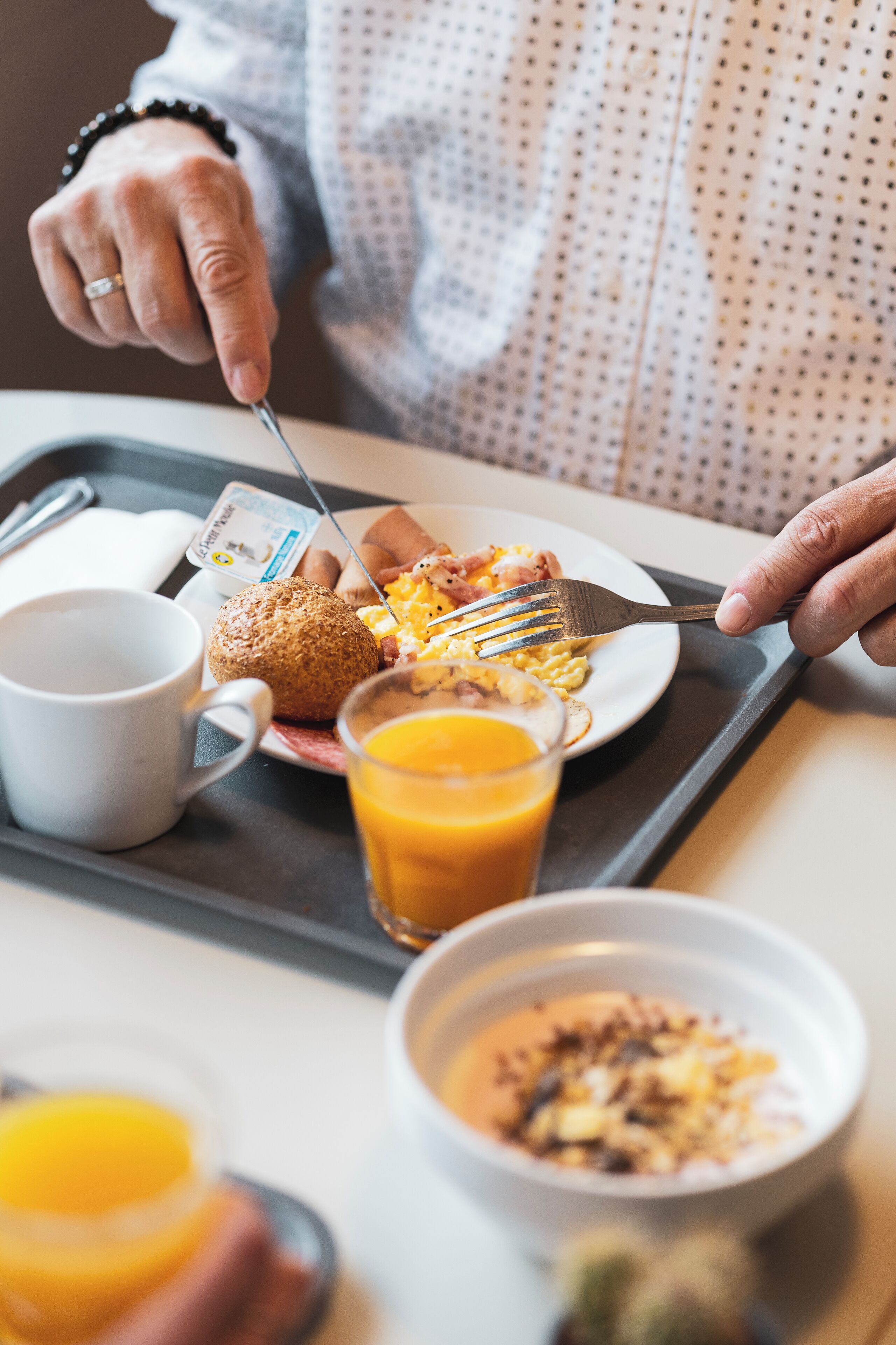 A tray with breakfast items including eggs, toast, and orange juice.