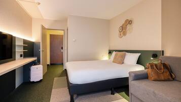 Una habitación de hotel moderna con una cama, un sofá, un escritorio y una maleta.