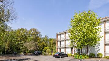 A parking lot with several cars, a building with a brick facade, and trees in the background.