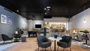 Un espace de détente moderne comprenant une table de billard, des sièges confortables, un bar et des œuvres d’art accrochées aux murs.