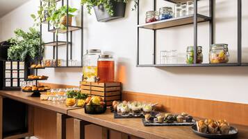 Ein Frühstücksbuffet mit verschiedenen Speisen, Glasbehältern und Topfpflanzen.