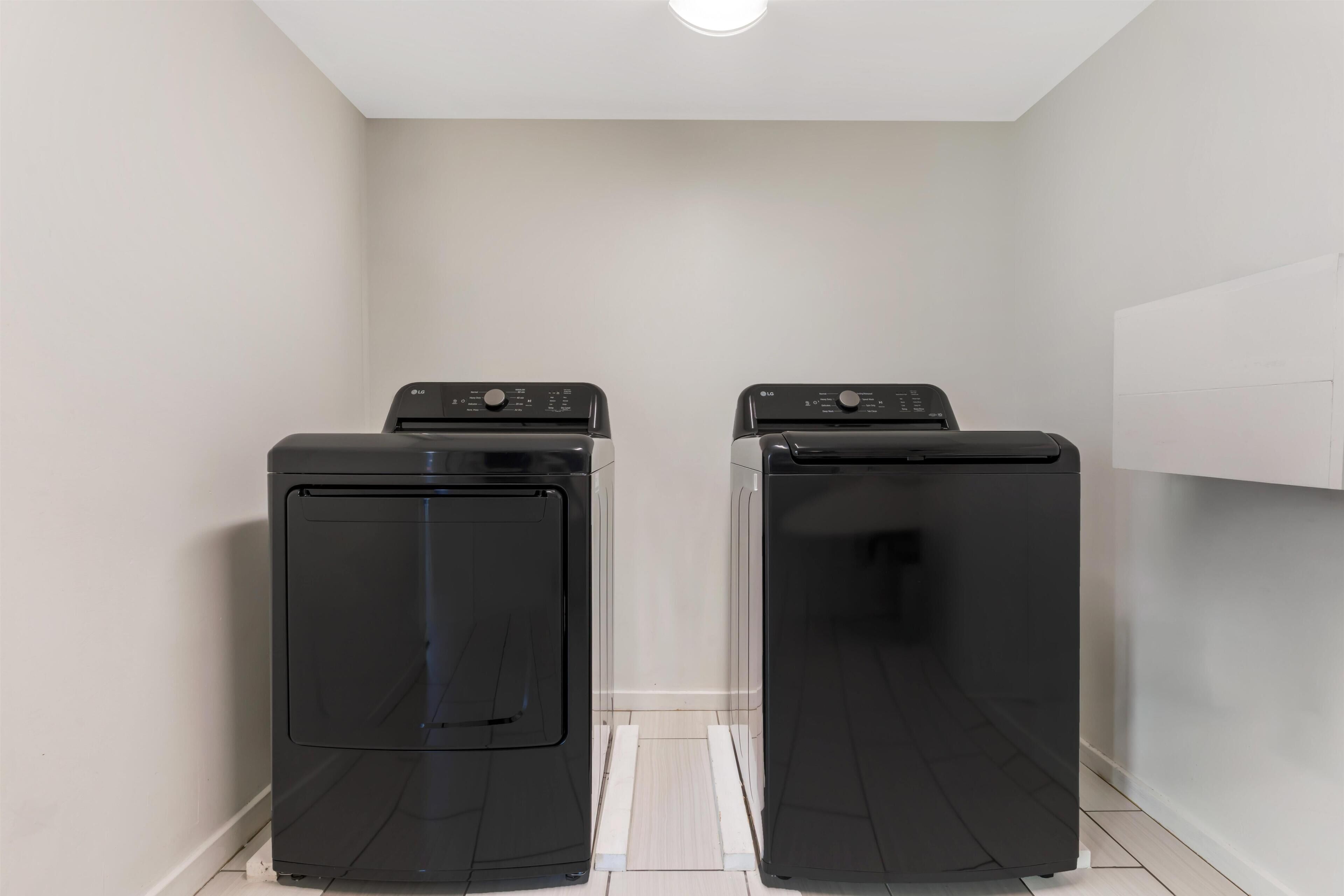 A laundry room with two black washing machines and a white wall.