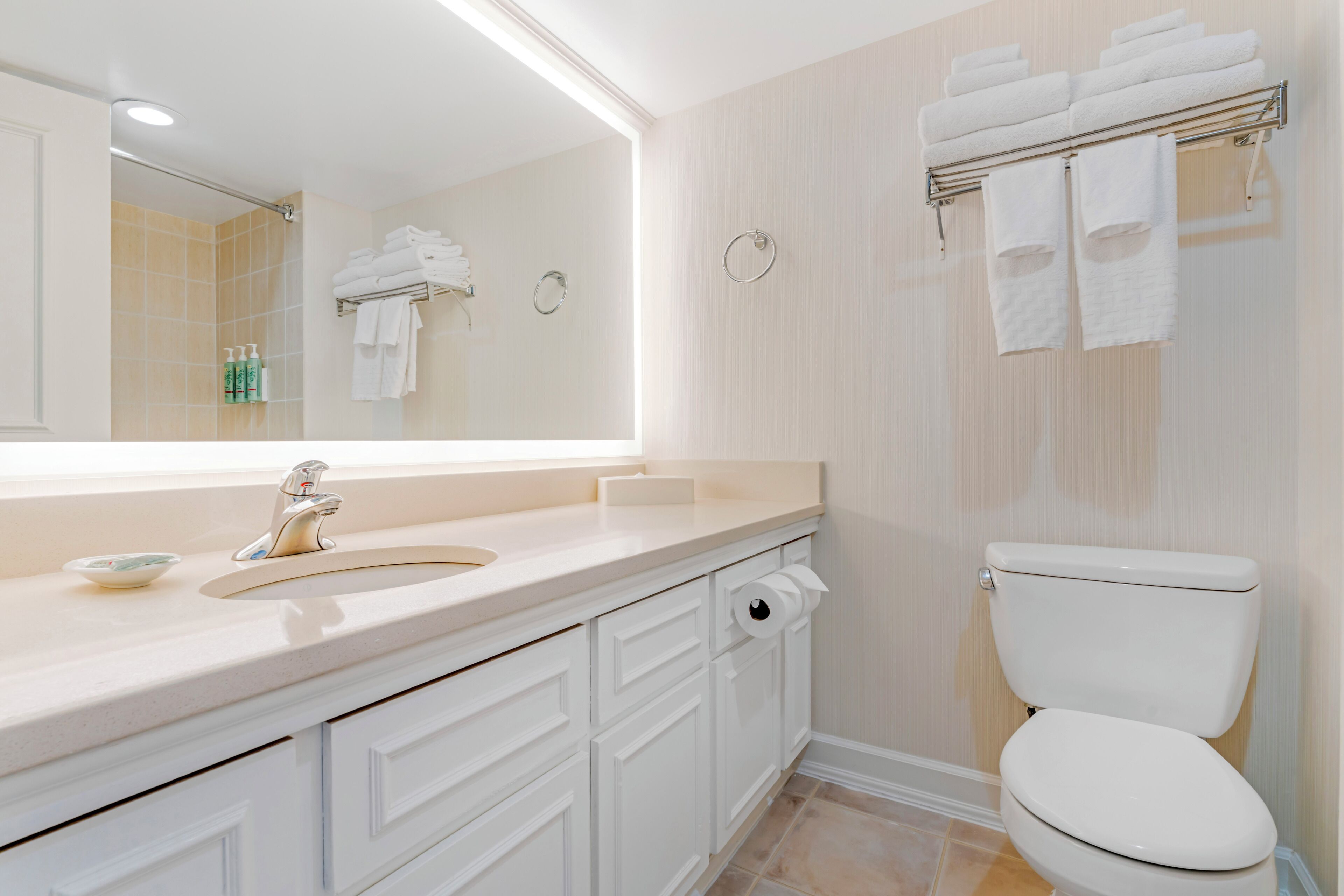 Un baño moderno con lavamanos, espejo, inodoro y toallero.