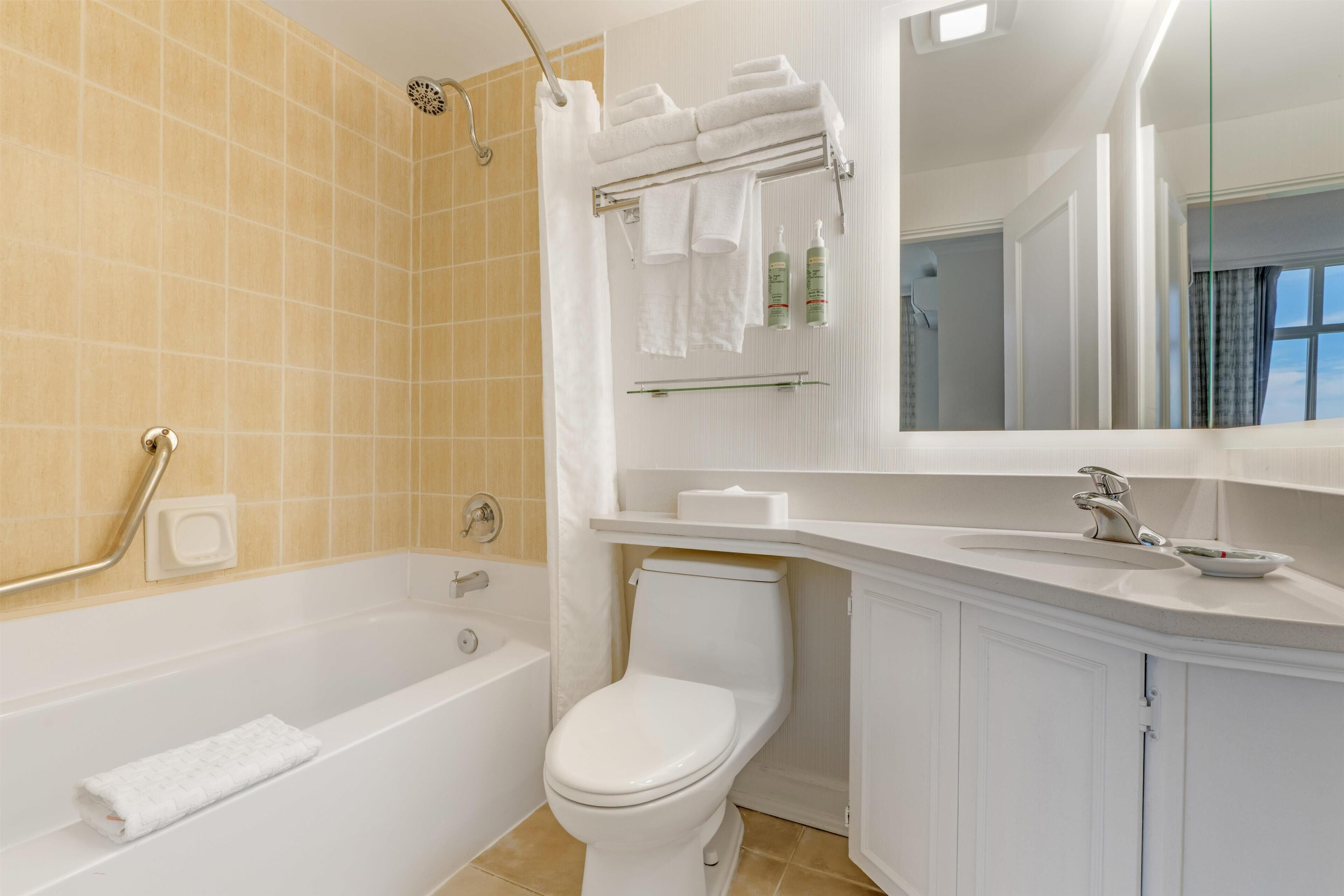 A bathroom with a bathtub, toilet, and a vanity with a mirror.