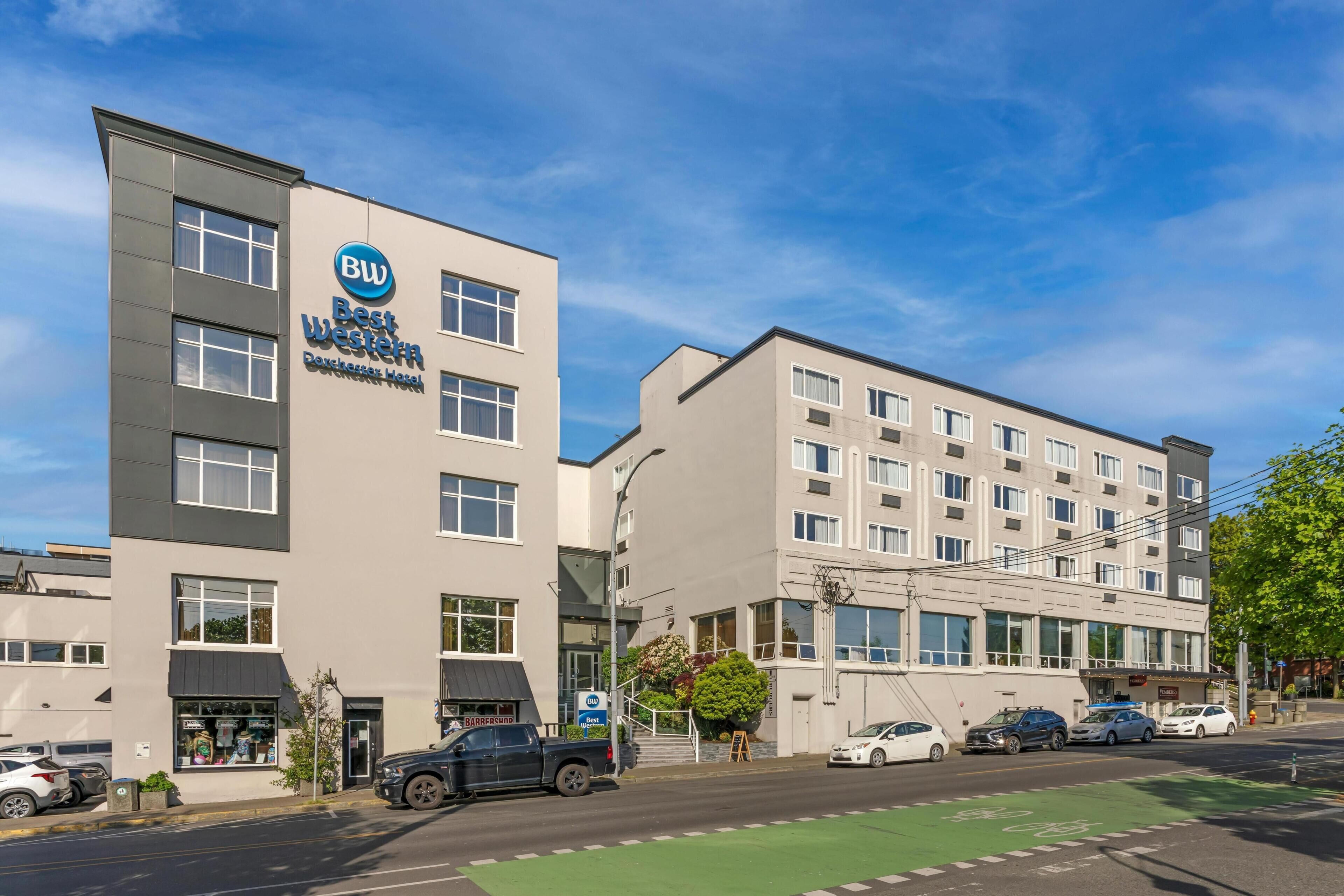 Een hotel met modern design, een goed zichtbare ingang en een parkeerplaats met auto's.