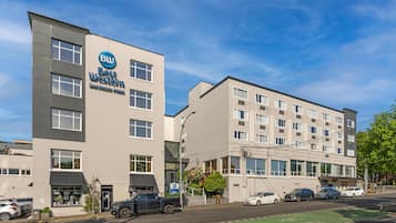 Een hotel met modern design, een goed zichtbare ingang en een parkeerplaats met auto's.