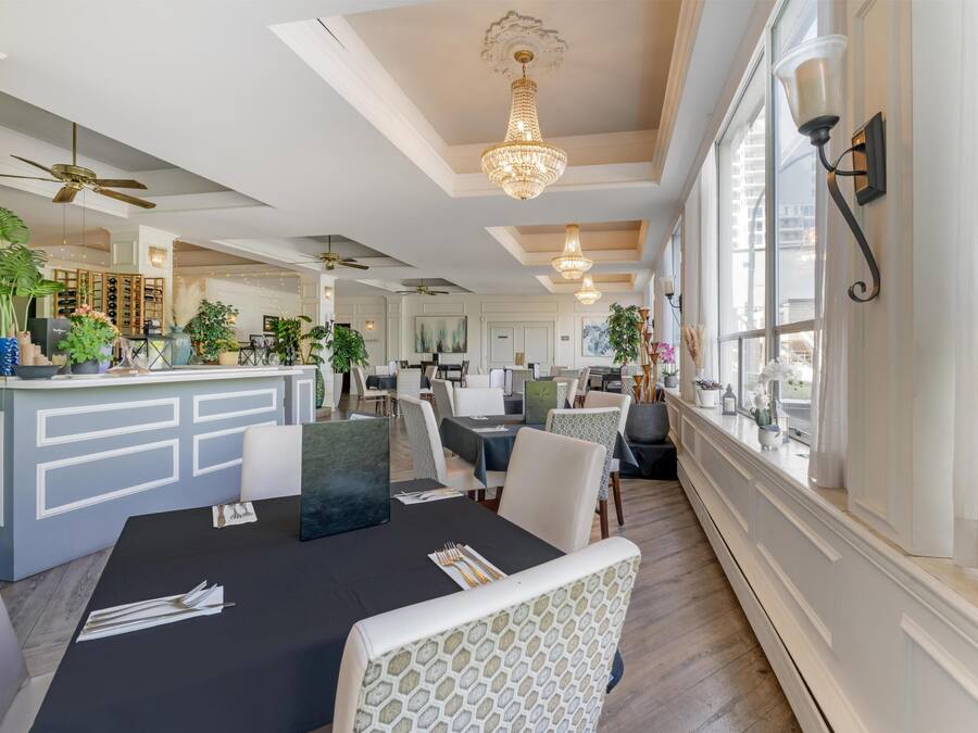 A dining area with a black tablecloth, white patterned chairs, and a chandelier.