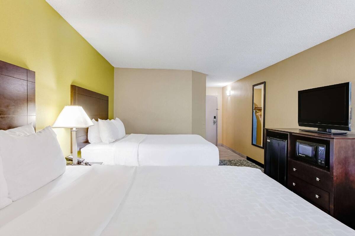 A hotel room with two beds, a TV, a lamp, and a minibar.