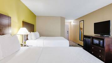Une chambre d’hôtel avec deux lits, une télévision, une lampe et un mini-bar.