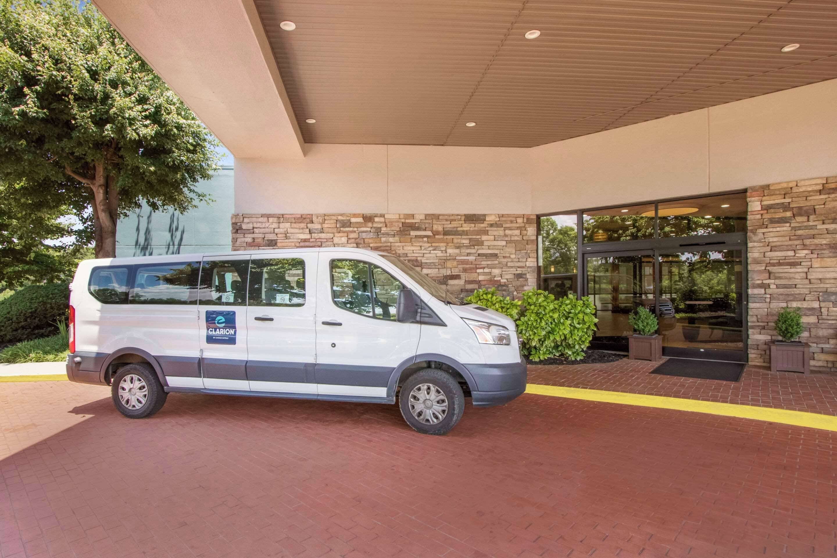 A white van parked in front of a building with a stone facade and a glass entrance.