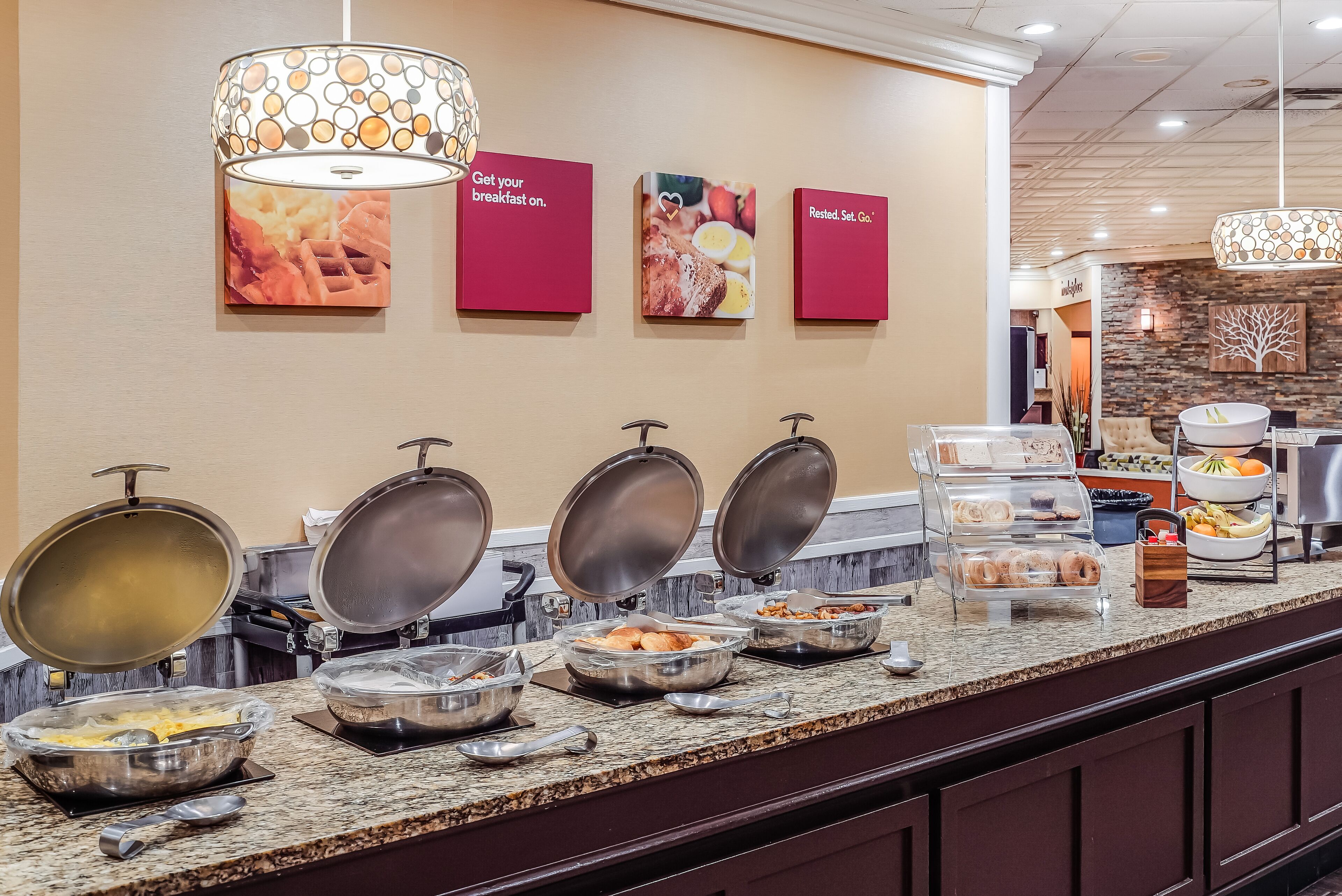 A buffet area with various food items and a sign indicating breakfast availability.