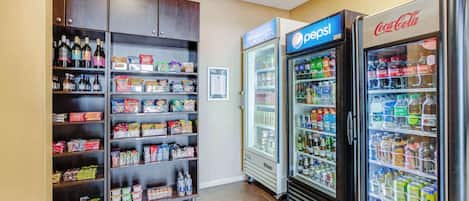 Ein Verkaufsautomatenbereich mit Kühlschränken für Pepsi und Coca-Cola, Snackregalen und einer Auswahl an Getränken.