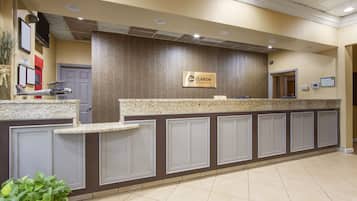 A reception area with a marble counter, a sign for 'Clarion by Choice Hotel', and a plant in the foreground.