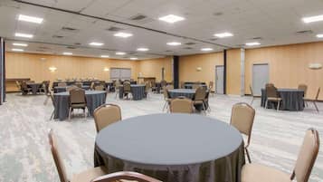 A conference room with multiple tables and chairs, equipped with a whiteboard and presentation screen.