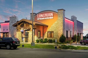 Un restaurante de carne con fachada de piedra y un letrero llamativo.