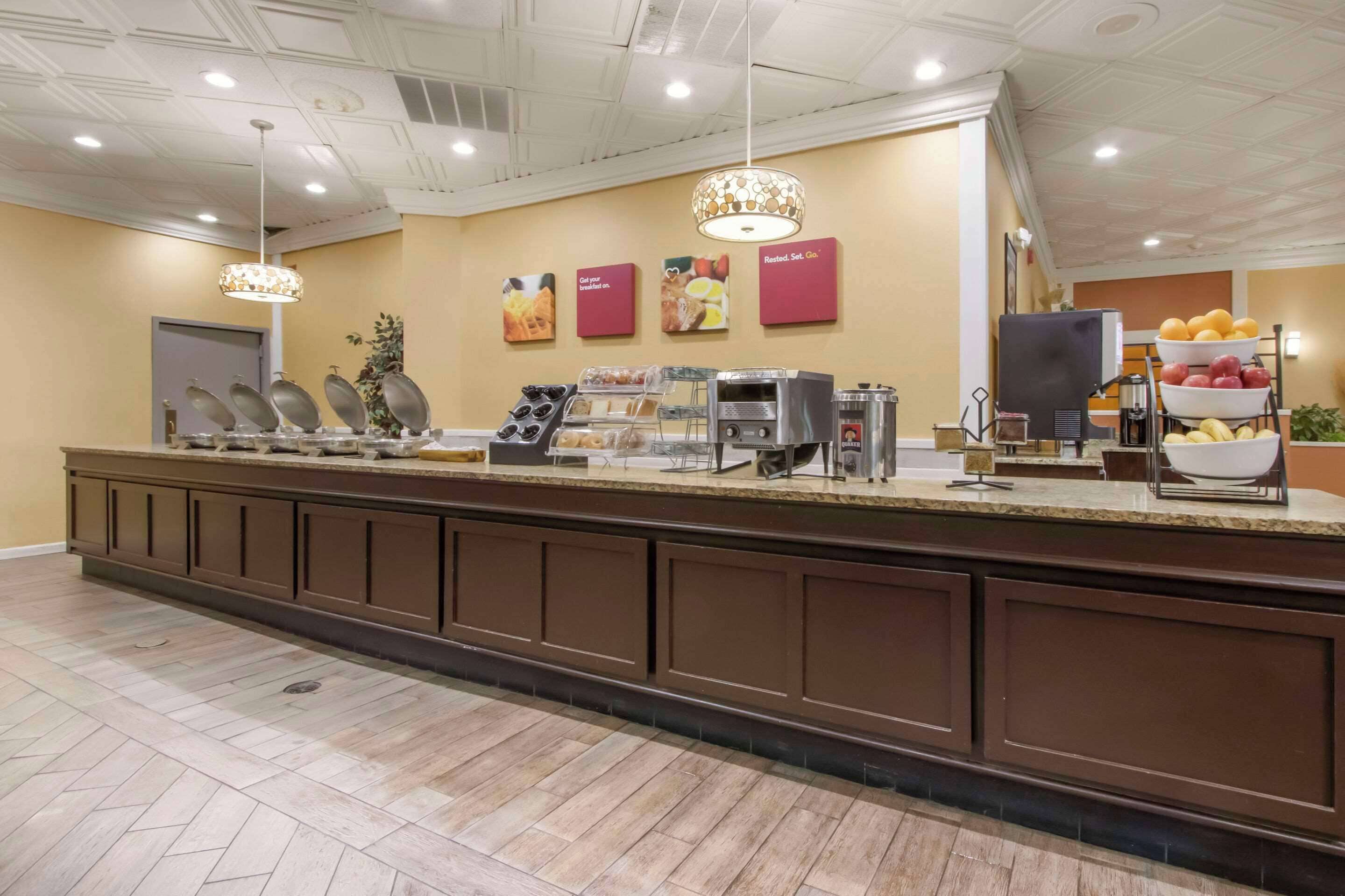 A buffet area with a long counter, various food stations, and a fruit display.