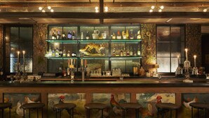A bar with multiple shelves of bottles and glasses, bar stools, and a mural of roosters. - Graduate by Hilton Oxford (Oxford)