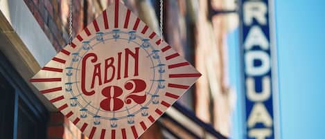 Un letrero colgante con el texto 'Cabin 82' y un diseño circular con faroles.