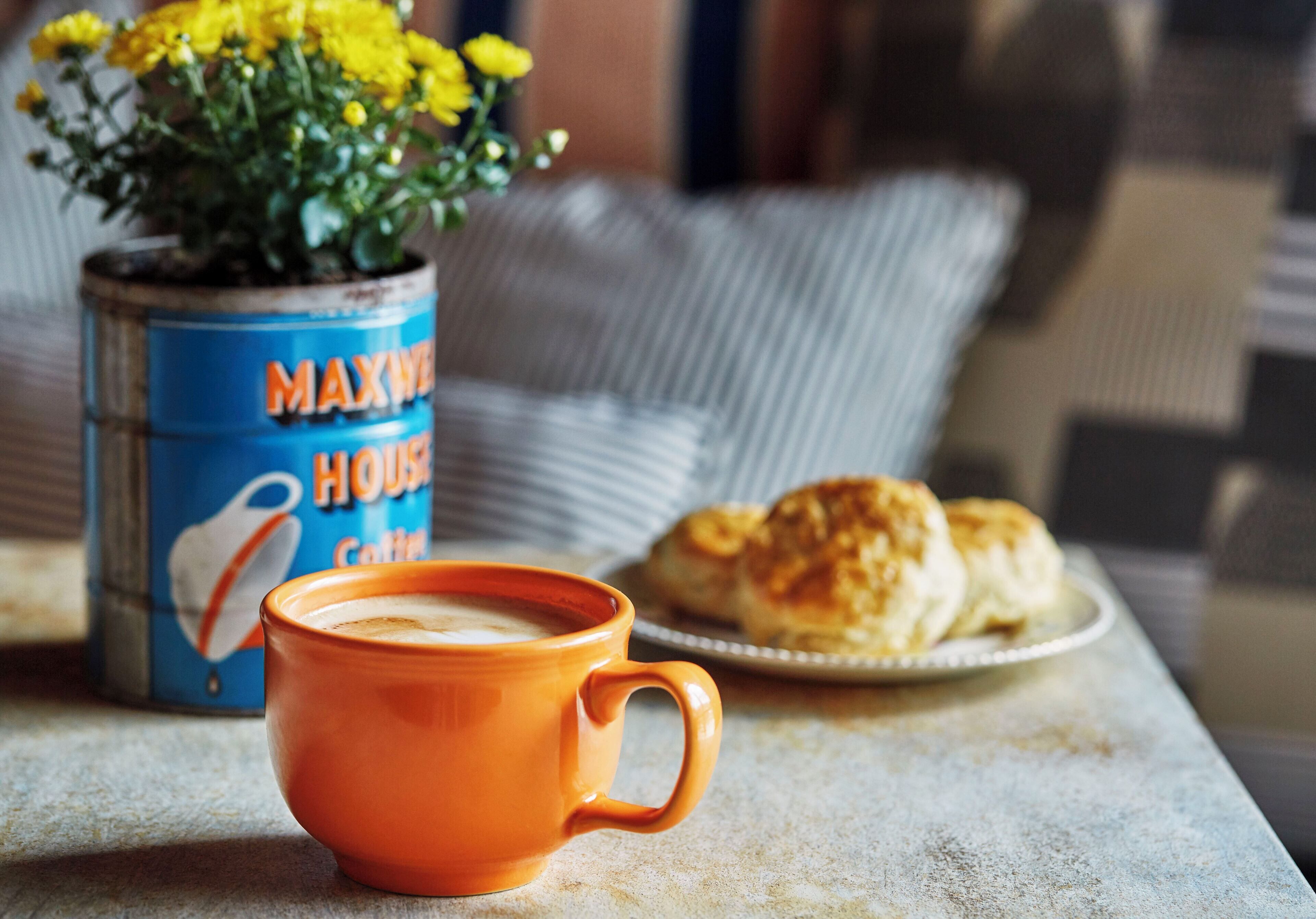Une table avec une tasse de café, un récipient étiqueté « Café MAXWELL HOUSE » et une assiette de viennoiseries.
