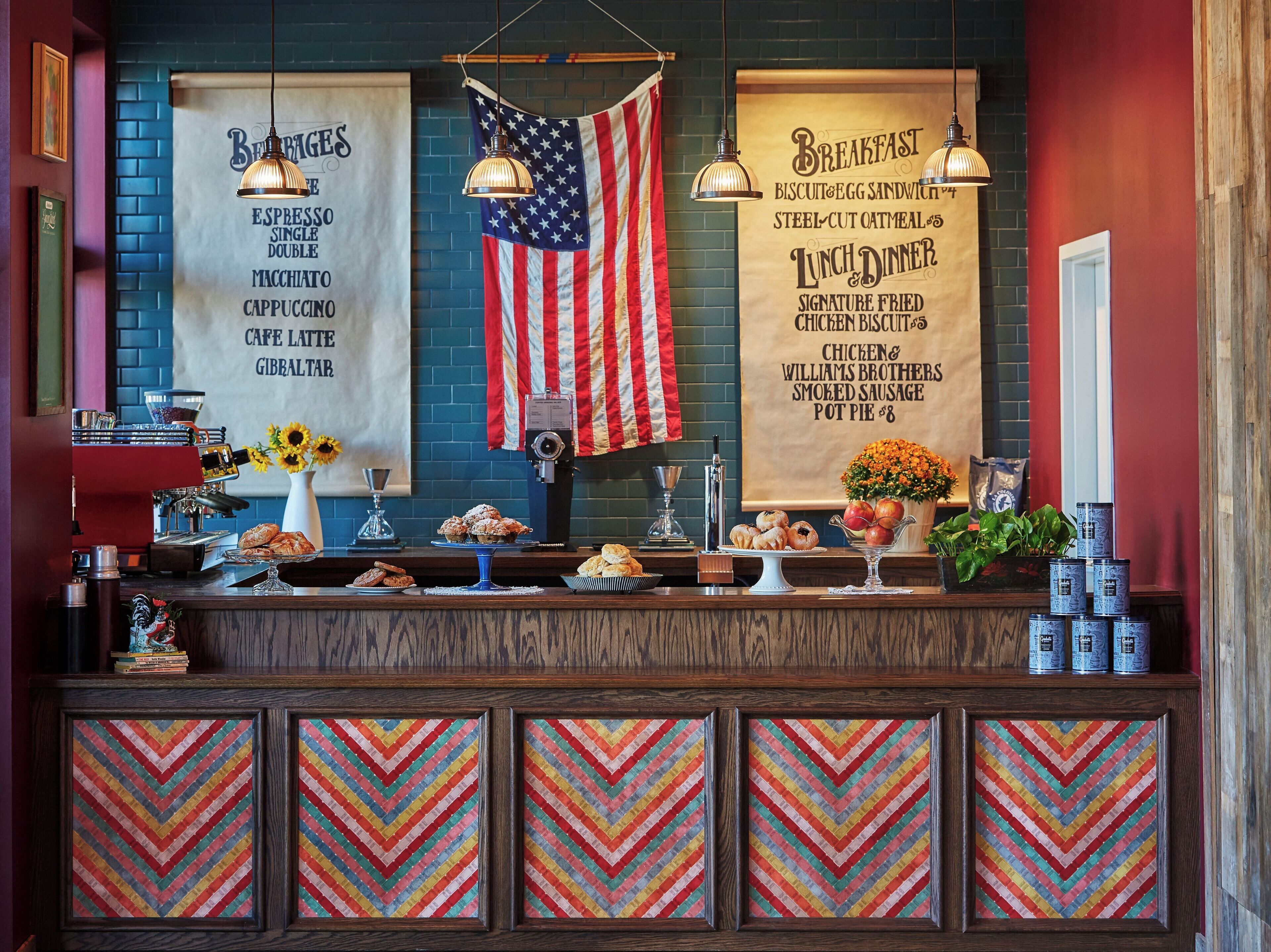 Mostrador de cafetería con un menú, una bandera estadounidense y diversas opciones de repostería.