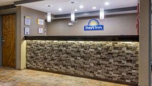 A reception area with a Days Inn sign, a tiled wall, and a wooden door. - Days Inn by Wyndham Florence Cincinnati Area (Florence)