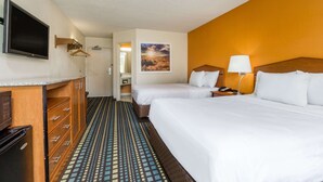 A hotel room with two beds, a television, a desk with a lamp, and a patterned floor. - Days Inn by Wyndham Florence Cincinnati Area (Florence)
