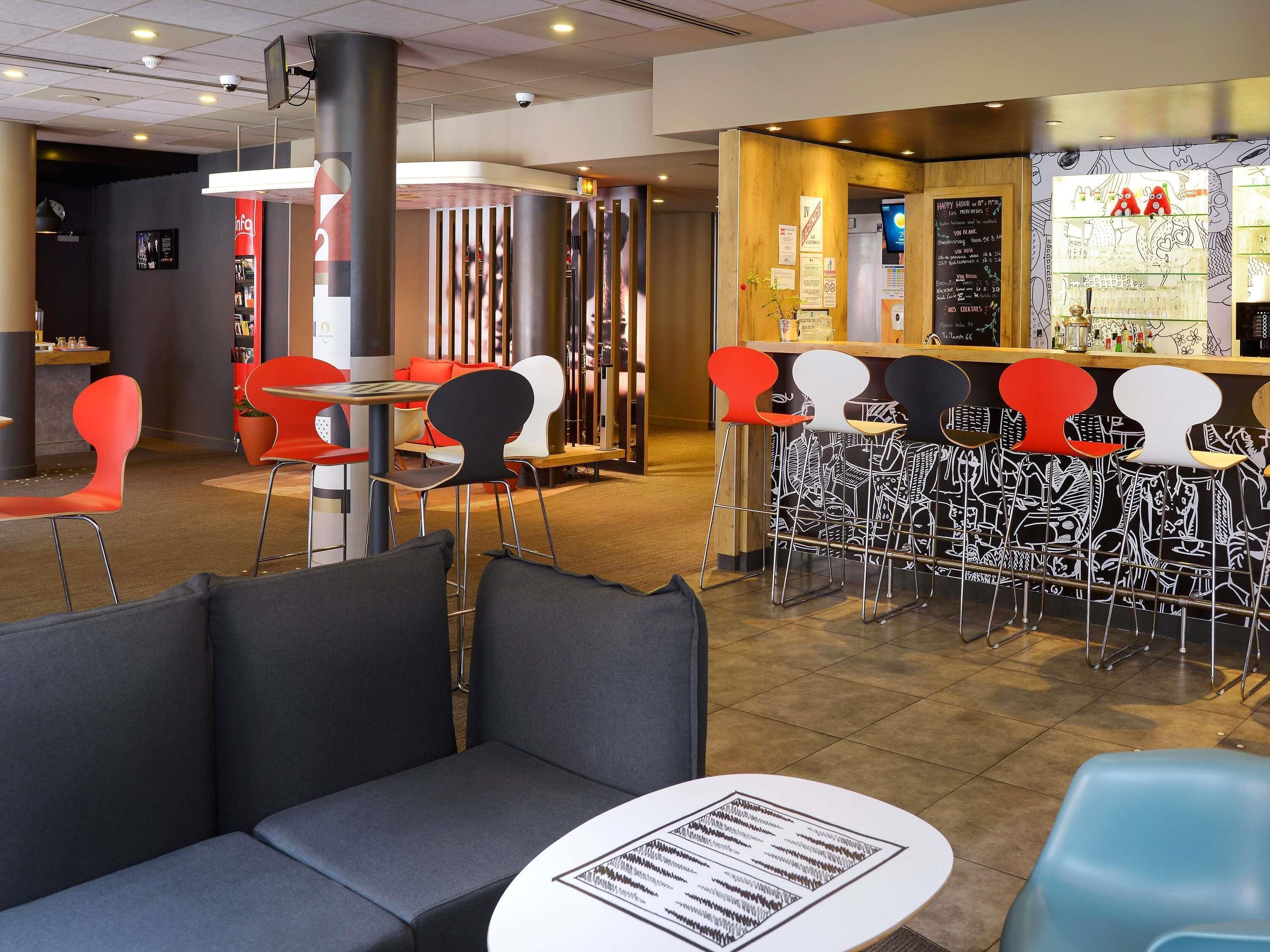 Un restaurante moderno con zona de bar, asientos con sillas coloridas y un tablero de menú.